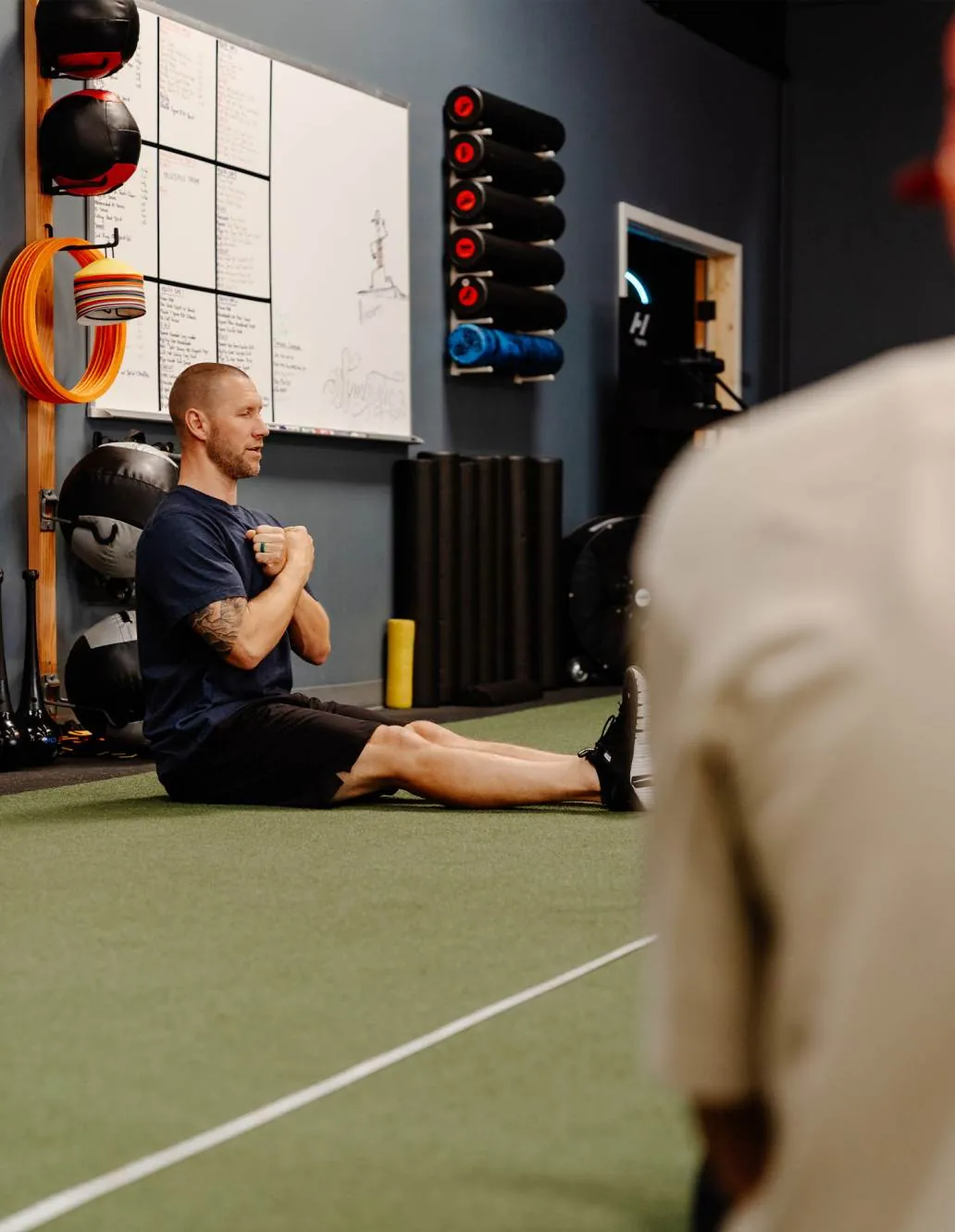 A coach working with an athlete on the training floor at Symbiotic Training Center