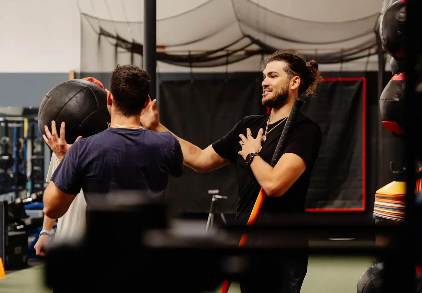 Two athletes working through a partner medicine-ball drill while a third looks on