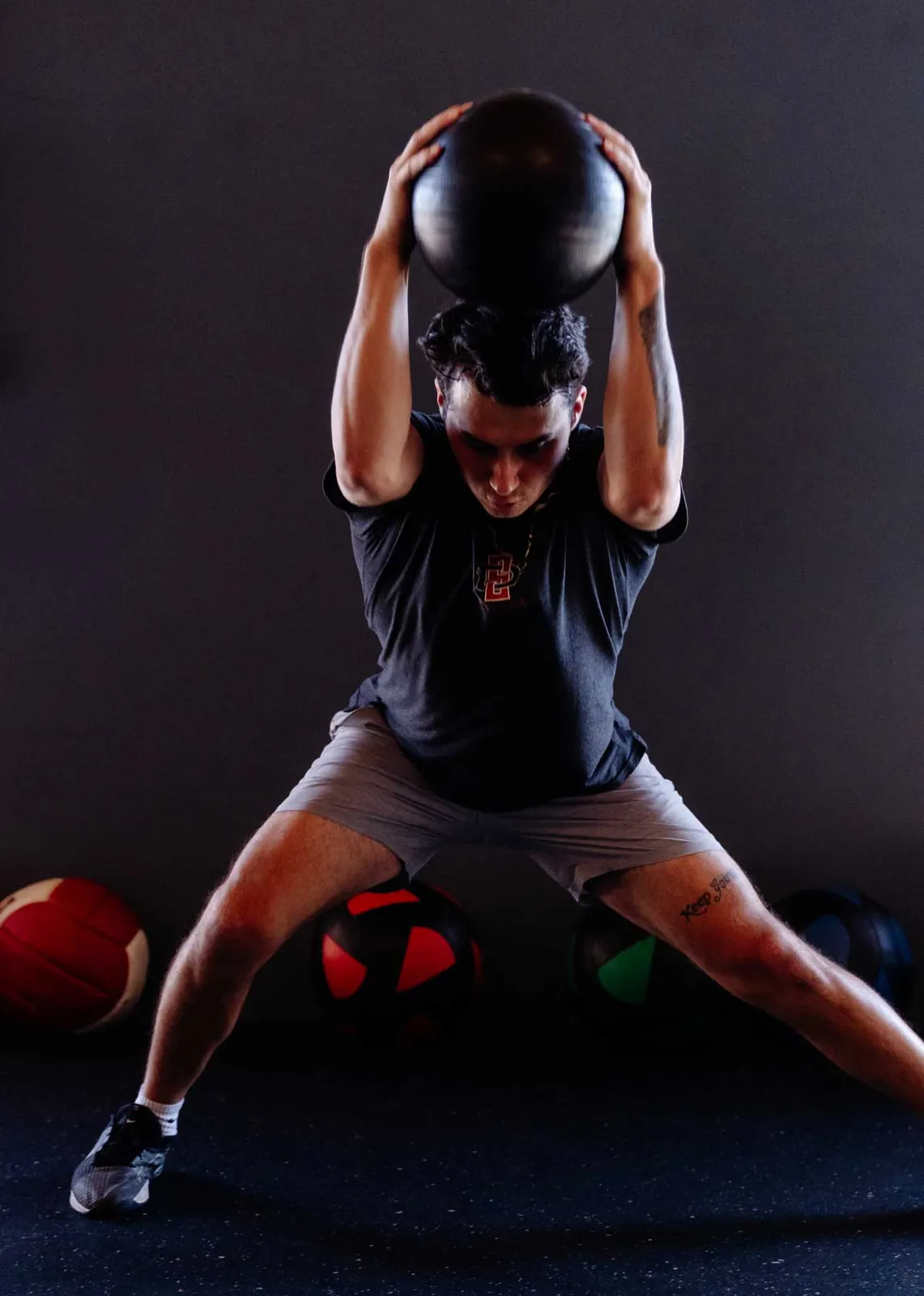 An athlete holding a medicine ball overhead in a deep squat